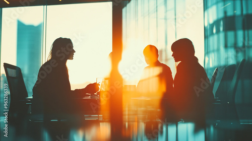 Business professionals in a modern boardroom at sunset, engaged in a discussion about a project