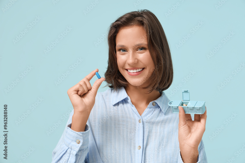 Pretty young woman with pill and organizer on blue background Pretty young woman with pill and organizer on blue background