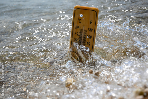 Obraz na plátne Wooden thermometer measuring increasing temperature of sea water during heat wav