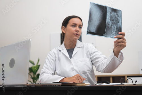 Young doctor examines x-rays pictures sitting in office female traumatologist diagnoses patient working with results of medical examination modern diagnostics