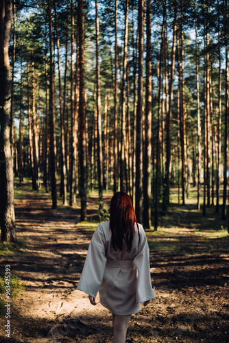 red-haired girl in a kimono dress walks through a pine forest