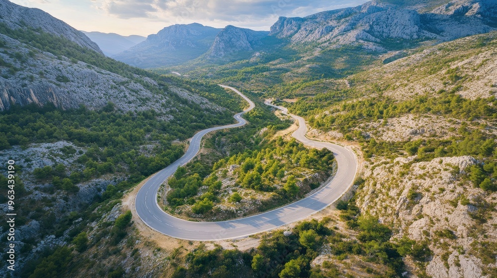 Fototapeta premium A picturesque aerial view of a road winding through a mountain range, capturing the beauty of travel by car through scenic landscapes