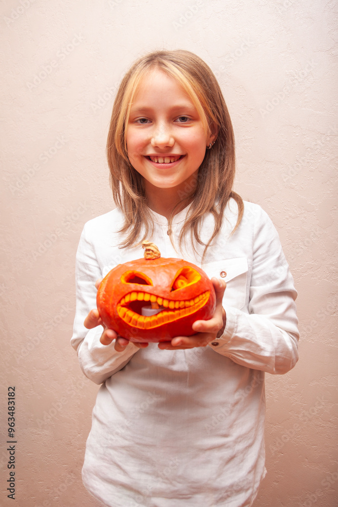 smiling girl child teenager in white shirt on plain background holding jack o lantern carved halloween pumpkin with teeth jack-o'-lantern smiling girl child teenager in white shirt on plain background holding jack o lantern carved halloween pumpkin with teeth jack-o'-lantern