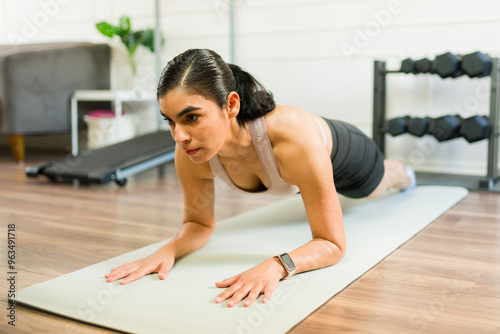 Wallpaper Mural Active Latin woman performing a plank exercise on a yoga mat during her home workout in the living room Torontodigital.ca