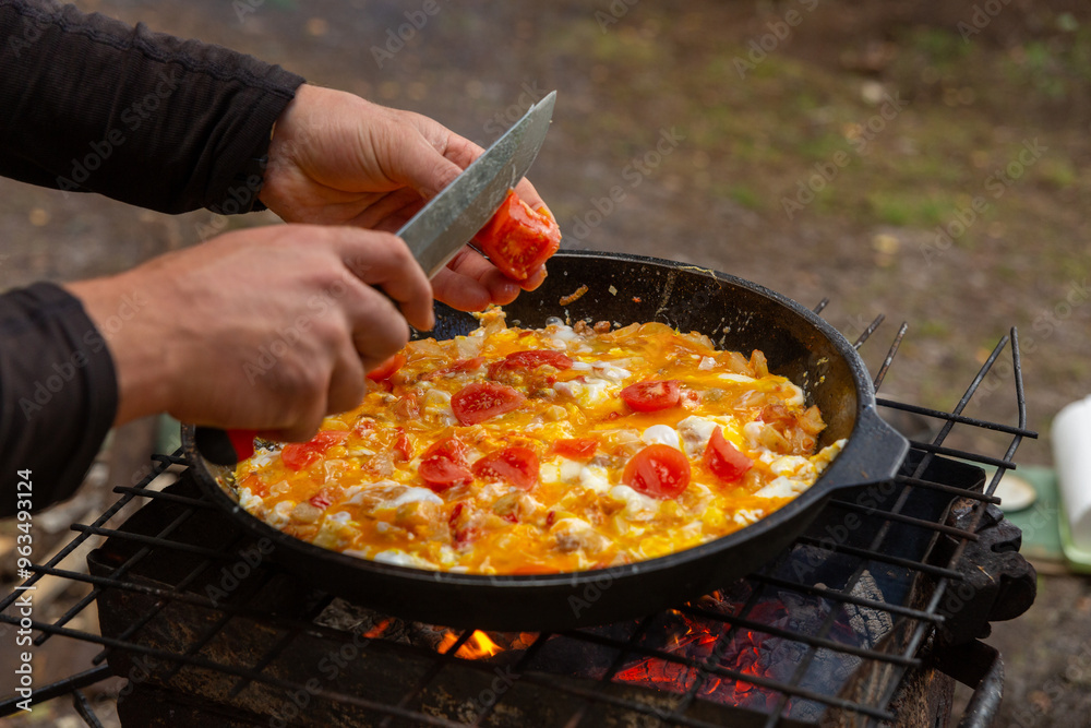A man slices tomatoes in order to fry them with eggs A man slices tomatoes in order to fry them with eggs