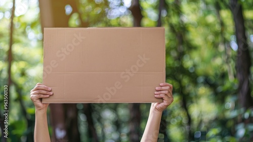 Blank Cardboard Sign Held Up In Front of Green Bokeh Background