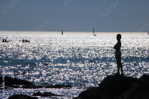 silhouette au coucher de soleil d'un garçon admirant l'océan photo