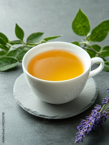 A cup of steaming lavender tea sits on a slate coaster, surrounded by delicate lavender sprigs and lush green leaves. This image embodies relaxation, tranquility, and the natural beauty of herbal infu photo