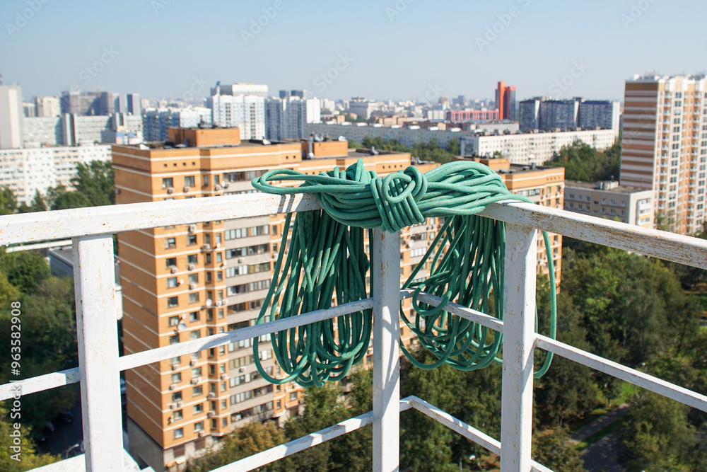 A coil of rope lying on the railing of a high-rise building's roof against the backdrop of a city. A coil of rope lying on the railing of a high-rise building's roof against the backdrop of a city.