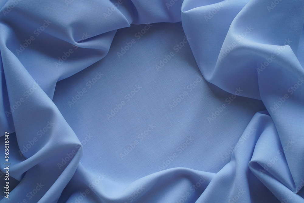 Blue textile background. Template with a frame of folds of plain cotton fabric. Close-up of threads of woven material, top view, copy space in the center. Blue textile background. Template with a frame of folds of plain cotton fabric. Close-up of threads of woven material, top view, copy space in the center.