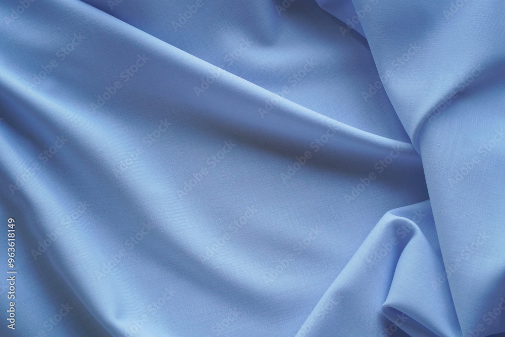 Cotton fabric with soft pleats as blue textile background with space for copying. Monochrome satin material close-up with texture and details. Cotton fabric with soft pleats as blue textile background with space for copying. Monochrome satin material close-up with texture and details.