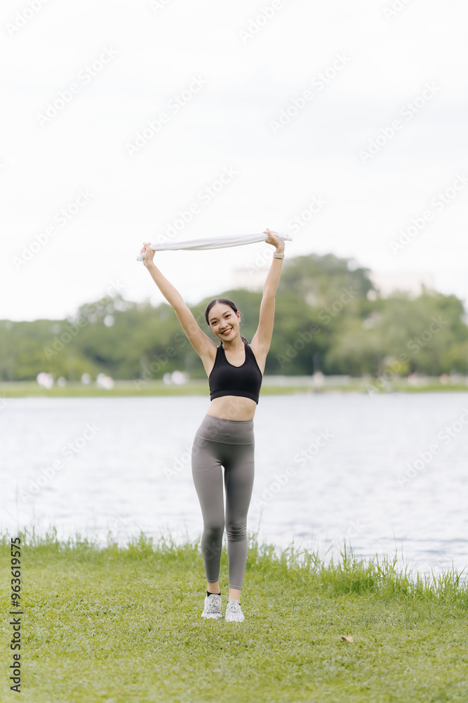 Radiant Runner's Triumph: A young woman celebrates her workout success, holding a towel high with a radiant smile, embracing the joy of fitness in a serene park setting. Radiant Runner's Triumph: A young woman celebrates her workout success, holding a towel high with a radiant smile, embracing the joy of fitness in a serene park setting.