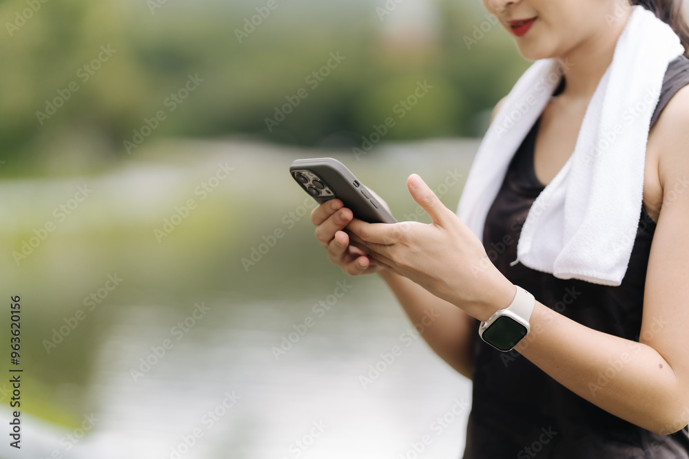 Fitness Focus: Young woman in sportswear checks fitness tracker app on smartphone during outdoor workout, showcasing technology integration in active lifestyle Fitness Focus: Young woman in sportswear checks fitness tracker app on smartphone during outdoor workout, showcasing technology integration in active lifestyle