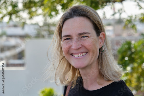 A mature smiling woman standing smiling in the garden in summertime