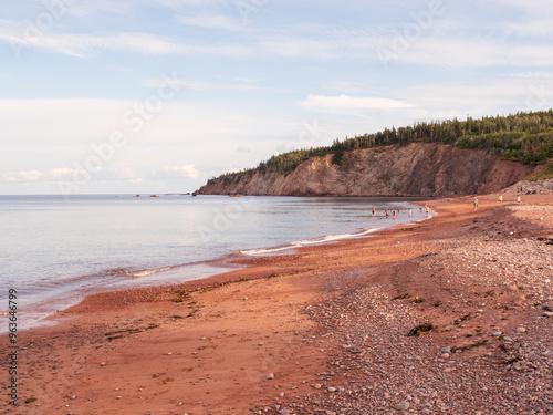 Visitors enjoying the red sandy shores of Broad Cove Beach in Cape Breton Highlands National Park, Nova Scotia, Canada