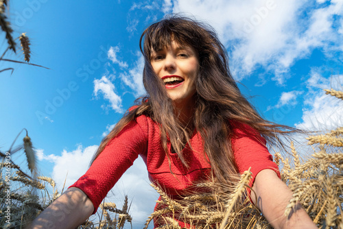 Junge attrakive Frau blickt durch reife Getreideähren auf den Ackerboden, Nahaufnahme. photo