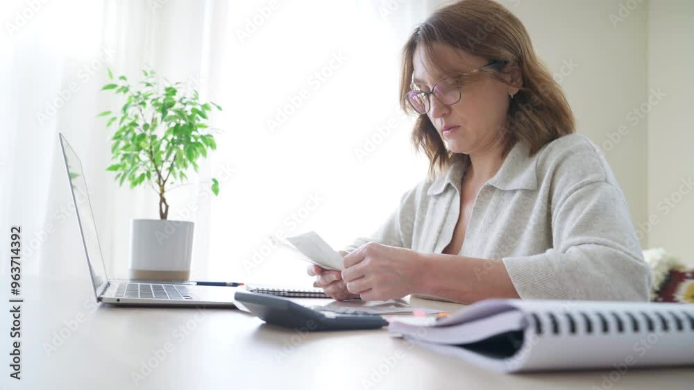 Beautiful middle-aged woman in glasses and paper bills using calculator while summing expences home office. Small business, successful investment, bull market, money savings concept 4K footage. Beautiful middle-aged woman in glasses and paper bills using calculator while summing expences home office. Small business, successful investment, bull market, money savings concept 4K footage.