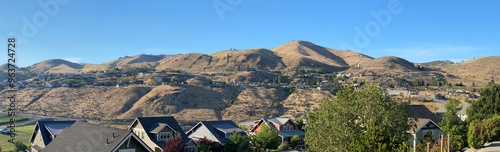 A panoramic view of the arid hillsides above the rooftops of houses at Chelan, Washington on a beautiful summer day_06212024_0001.