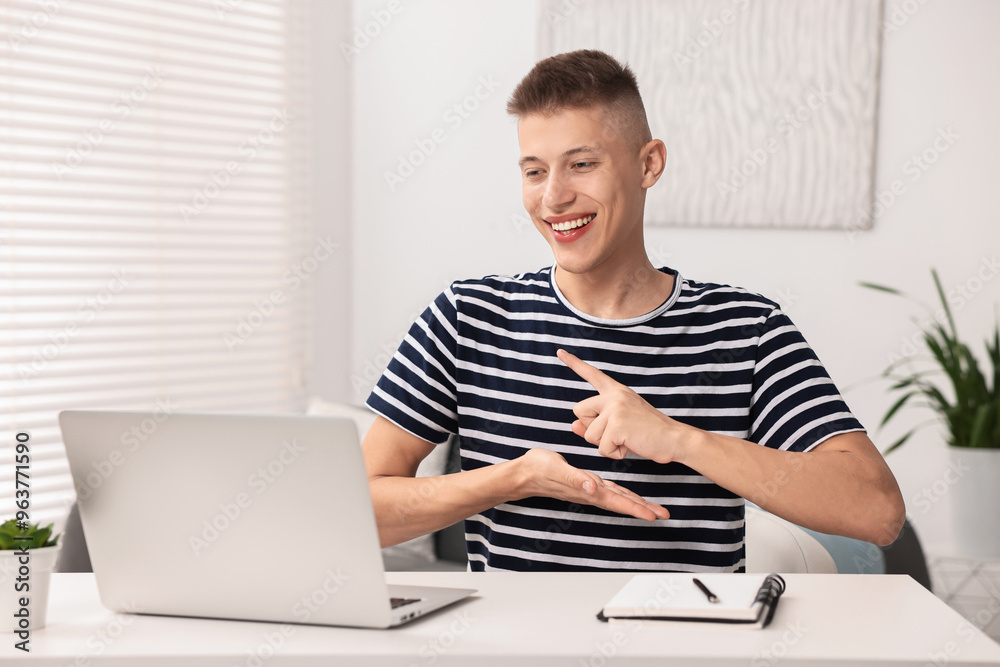 Young man using sign language during video call indoors Young man using sign language during video call indoors