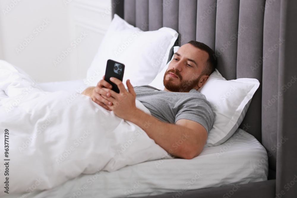 Handsome man using mobile phone in bed Handsome man using mobile phone in bed
