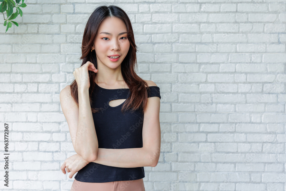 Smiling Young Woman Posing Casually in Black Top Against White Brick Wall
