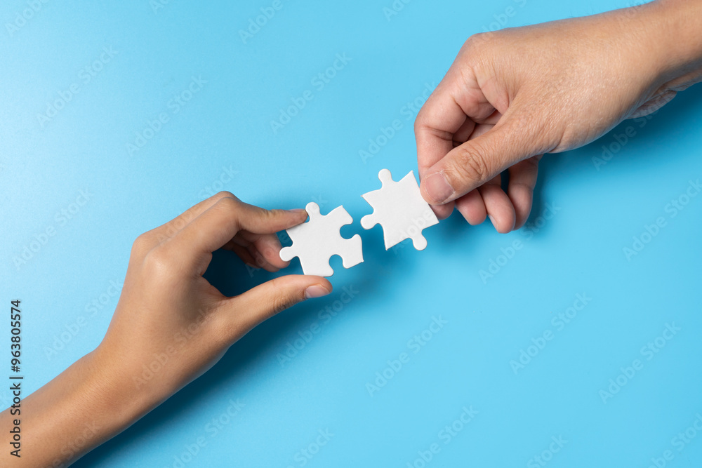 Two Hands Connecting Puzzle Pieces on a Blue Background Two Hands Connecting Puzzle Pieces on a Blue Background