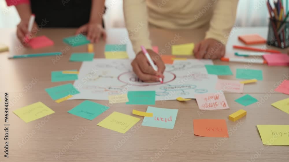 Slow motion hand closeup of startup employee team brainstorming strategic marketing plan and making mind map with colorful sticky notes placed on office table at meeting room. Variegated Slow motion hand closeup of startup employee team brainstorming strategic marketing plan and making mind map with colorful sticky notes placed on office table at meeting room. Variegated