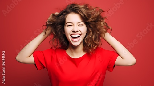 Woman in red sweater points with both hands, standing against an orange background.