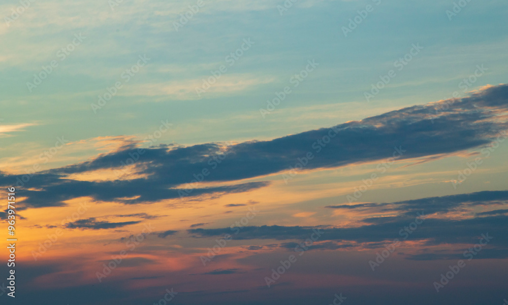 Cumulonimbus mother cloud dissipating into stratocumulus cumulonimbogenitus and Altocumulus clouds at dusk colored by the sun in different shades from yellow to orange