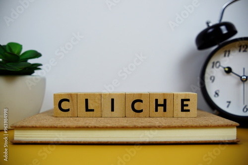 Alarm clock with wooden blocks alphabet letters CLICHE on yellow background photo