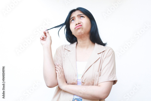 thougtful asian woman looking up to empty space and hold her hairs with pondering face expression wearing casual clothes isolated on white background photo