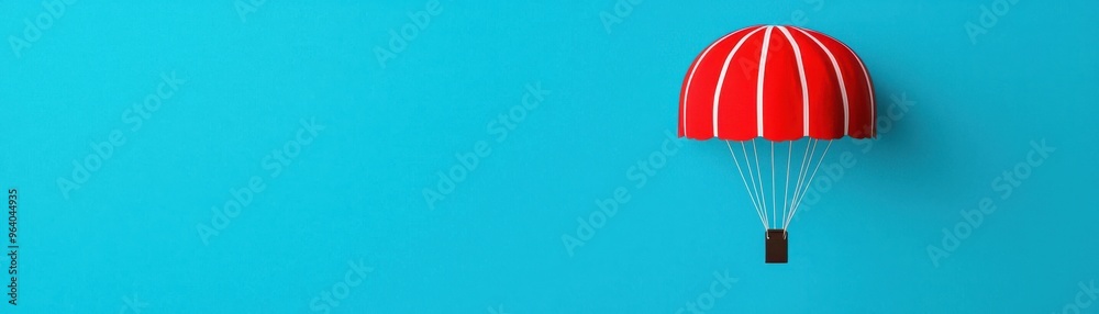 Obraz premium Colorful red parachute against a bright blue background, symbolizing adventure, freedom, and aerial sports.
