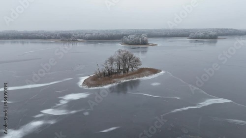 Frozen Rubikiai Lake in Lithuania on a foggy winter day. Aerial view of the frozen Rubikiai Lake in Lithuania, with snow-covered islands and foggy winter skies creating a serene scene. photo