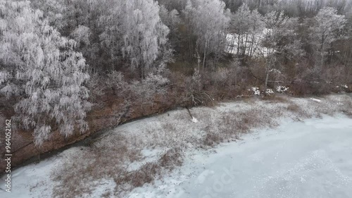 Frozen Rubikiai Lake in Lithuania on a foggy winter day. Aerial view of the frozen Rubikiai Lake in Lithuania, with snow-covered islands and foggy winter skies creating a serene scene. photo