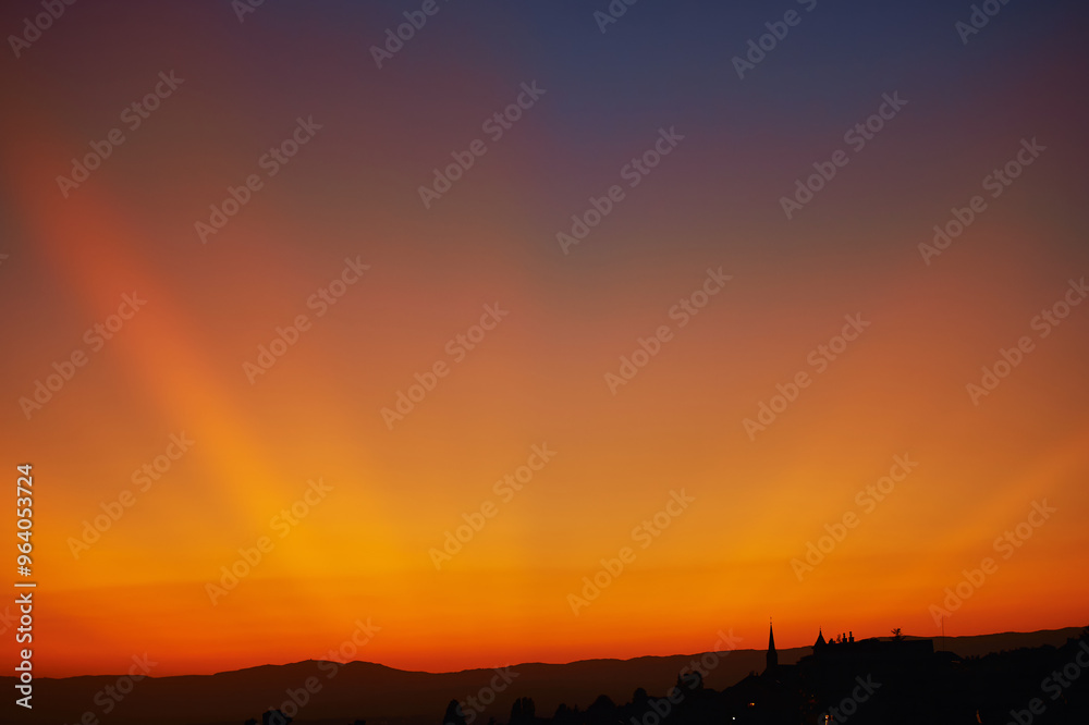 Beautiful sunset with dramatic orange yellow rays of light on dark blue sky Beautiful sunset with dramatic orange yellow rays of light on dark blue sky