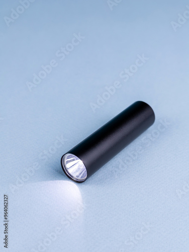 Close up of small and powerful handheld flashlight for travel on blue background