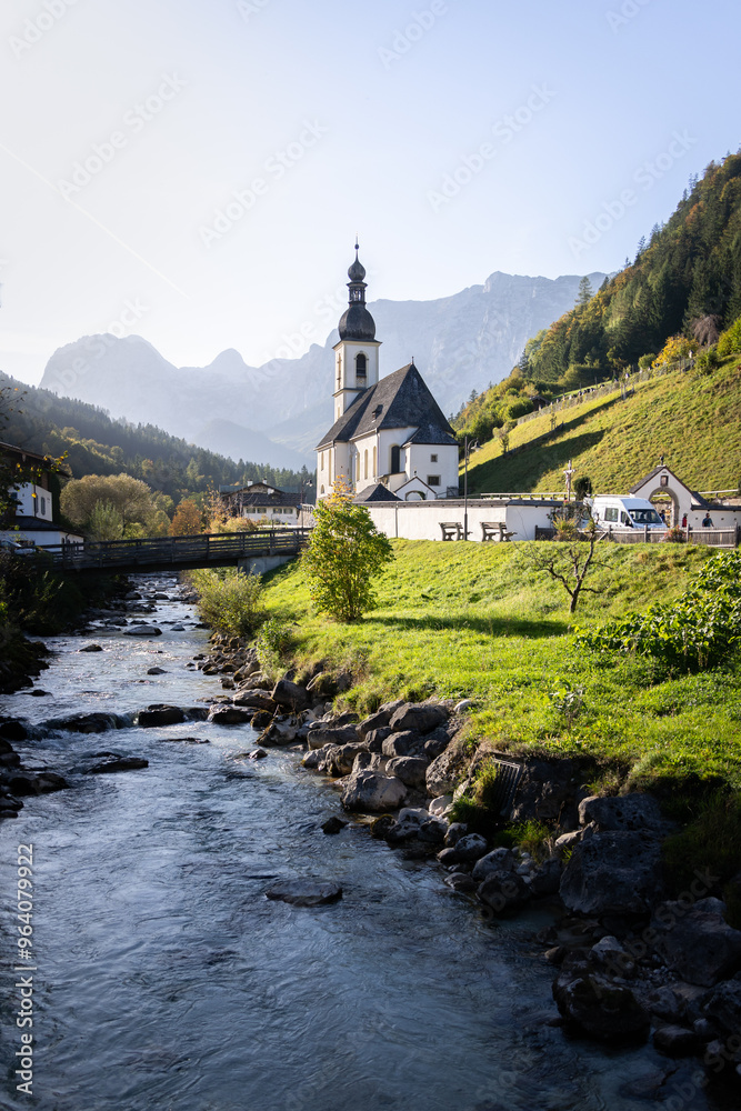 Vertical shot of picturesque church in alpine village surrounded by mountains and autumn trees Vertical shot of picturesque church in alpine village surrounded by mountains and autumn trees