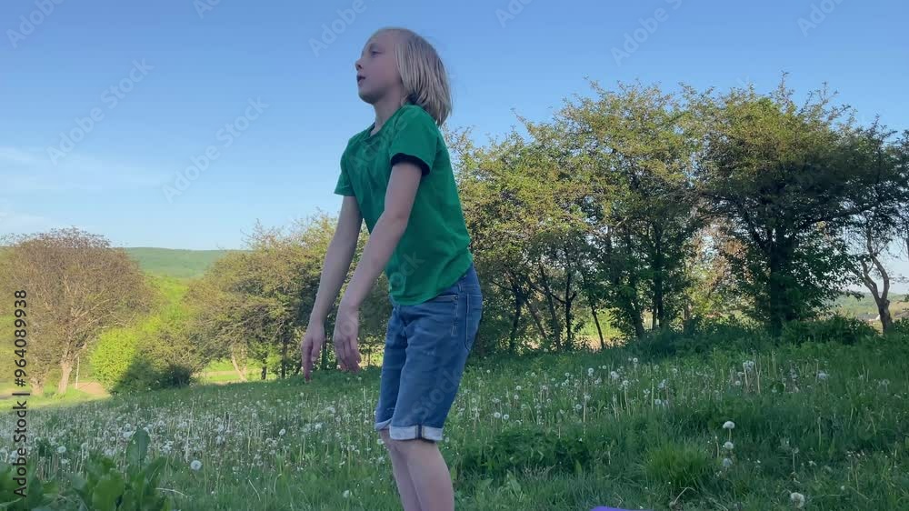 Young boy performing squats in a sunny field surrounded by trees, showcasing an active and healthy lifestyle Young boy performing squats in a sunny field surrounded by trees, showcasing an active and healthy lifestyle