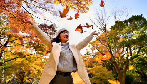 紅葉のきれいな公園で落ち葉を浴びる女性 photo