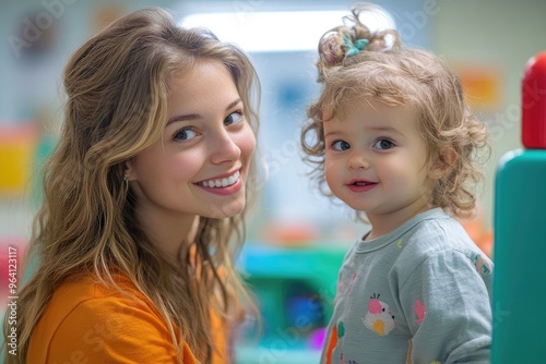 Kindergarten teacher smiling with baby girl in daycare center