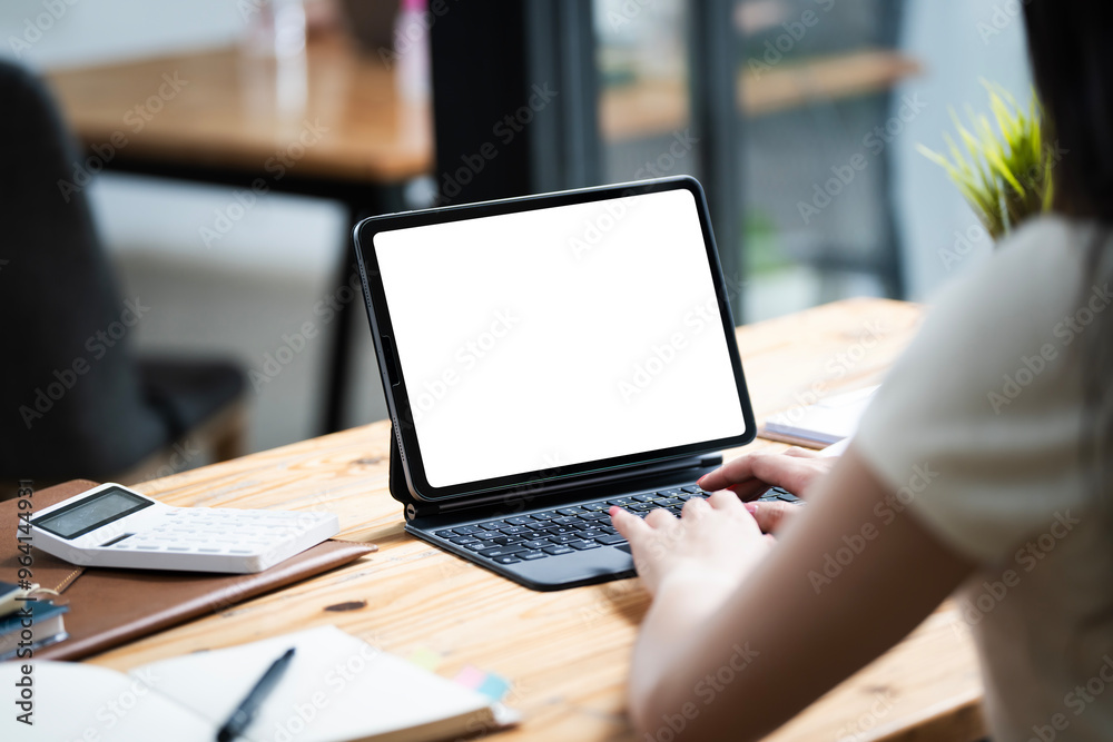 Woman typing on a laptop with a blank screen at a desk in a well-lit home office Woman typing on a laptop with a blank screen at a desk in a well-lit home office