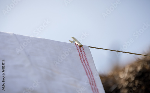 Textile clothes drying on a rope fixed with clips drying in the sun.