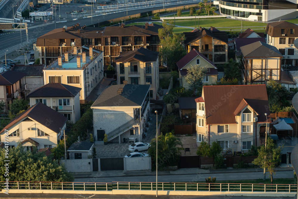Fototapeta premium Aerial view of residential houses in a modern suburban neighborhood with greenery and a highway in the background