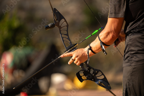 A man is holding a bow and arrow, pointing it at a target