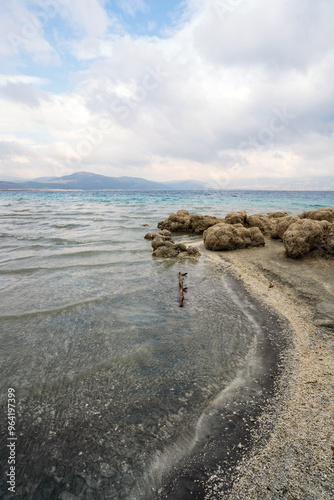 Obraz na płótnie Turquoise waters and white mineral beaches of Lake Salda, Turkey, with a cloudy sky and rocky formations in the background. w salonie