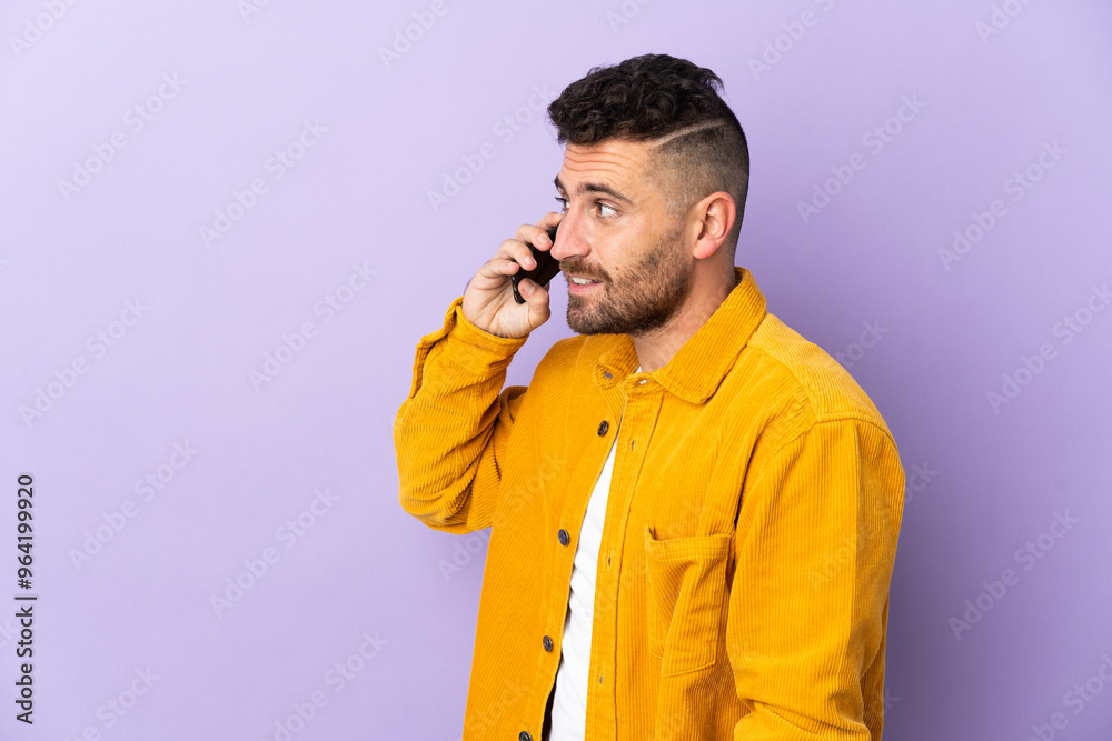 Caucasian man isolated on purple background keeping a conversation with the mobile phone with someone Caucasian man isolated on purple background keeping a conversation with the mobile phone with someone