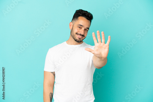 Young caucasian man isolated on blue background counting five with fingers