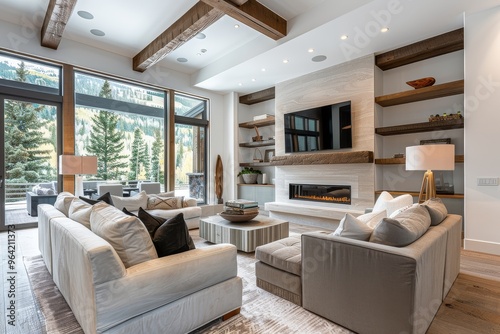 Elegant and modern Vail living room with natural wood flooring, white walls, light grey sofa and chairs, fireplace, wall-mounted TV, built-in art shelves, and a large table with lamps.