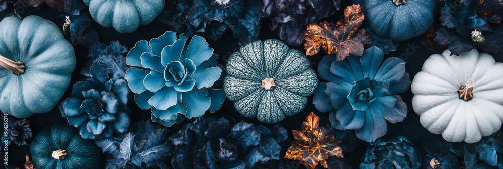 Fototapeta premium An artistic arrangement features various blue pumpkins and succulent plants surrounded by fall leaves, evoking a tranquil autumn vibe