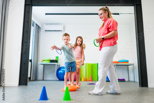 Kids group physio therapy. Children and female physical therapist exercising during session. Bilateral coordination or integration.